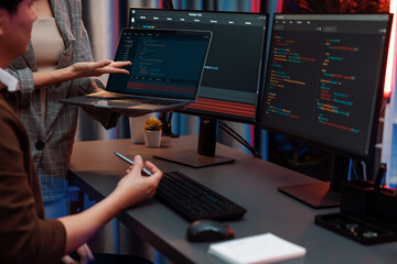 Serious of IT developers discussing intelligent website development coder system running data online two screens with laptop showing information network at neon light room at modern office. Infobahn.