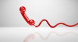A red telephone receiver with a coiled cord on white surface