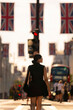 Unrecognized Latina woman walks with confidence and joy along Oxford Street in London, England during golden hour, wearing a black, surrounded by red buses, city lights, and Union Jack flags in summer