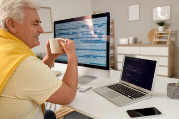 Senior programmer with coffee working at table in office