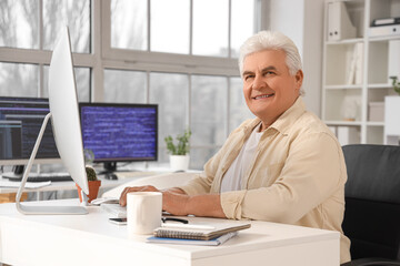 Senior programmer working at table in office