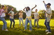 © Studio Romantic - Group of a young diverse students having fun in summer park. Happy girls and boys dancing on green grass outdoors. Smiling joyful people in casual clothes spending time together in nature.