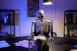 © Pixel-Shot - Human skeleton model sitting in office at night