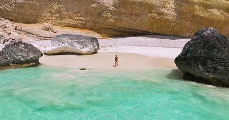 Wall Mural - Woman Running To The Ocean To Swim In The Crystal Clear Water Of Shoab In Socotra Island, Yemen. - aerial shot