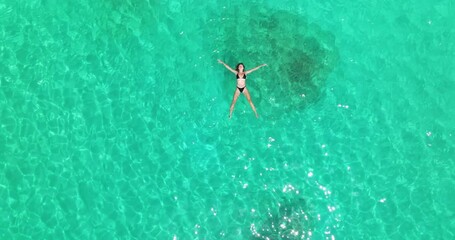 Wall Mural - Woman In Bikini Floating On Her Back In Clear, Turquoise Water In Shoab, Socotra Island, Yemen. - aerial shot