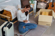 © itchaznong - Home Organization: Young Woman Writing Notes While Unpacking