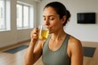 © Who is Danny - Woman in sportswear drinking herbal tea with lemon after yoga session in bright room with calm atmosphere and minimalist background. Ai generative