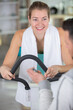 © auremar - woman using an exercise machine while personal trainer holds stopwatch