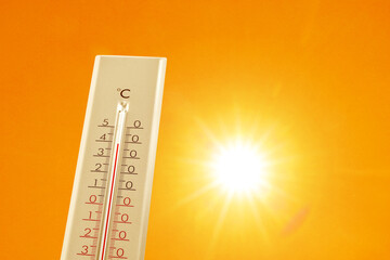 Wall Mural - thermometer showing high temperature against orange sky with bright sun. extremely hot weather
