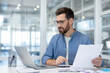 © Liubomir - Man working with laptop and documents in modern office