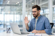 © Liubomir - Man video conferencing, waving hand during online meeting