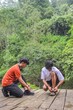 © Queenmoonlite Studio - Two Young Men Tying Shoelaces Before Hiking Through Lush Green Forest Trails Adventure Outdoors