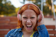 © Javier - Energetic woman expressing individuality and passion, shouting with enthusiasm while enjoying her music outdoors