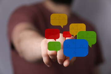 A hand points toward colorful speech bubbles made of puzzle pieces, symbolizing connectivity and idea sharing in communication.