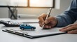 © Sam Efendi - Close-up of a hand signing a vital document, likely a car insurance policy or vehicle purchase agreement, with a miniature car on the desk