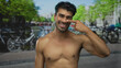 © Krakenimages.com - Man with bare chest smiles on a sunny street beside a canal lined with bicycles and greenery; serenity.