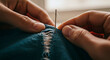 © BrunaIsabelle - Close-up of hands repairing torn denim with needle and thread, representing sewing, mending clothes, craftsmanship, and sustainable fashion practices.