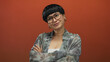 © Krakenimages.com - Young chinese woman smiling confidently in front of an isolated vibrant orange background, wearing stylish glasses and a floral shirt, embodying modern, positive, and casual vibes.