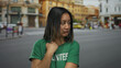 © Krakenimages.com - Woman in green volunteer t-shirt standing on city street with a concerned expression, reflecting urban life and youth involvement in outdoor volunteer activities.