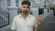 © Krakenimages.com - Young hispanic man waves finger in no gesture along sunlit city street with white building facade visible; refusal.