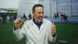 Man celebrating outdoors in pisa near iconic tower holding toothbrush with joyful expression in italy wearing white coat against blurred urban backdrop.