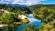 © Deri - Panoramic view of a river winding through lush green valleys under a partly cloudy sky