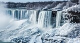 Niagara Falls frozen in winter.  Ice-covered cascades of water plunge from a snowy cliff face.  Trees and ground are coated in a thick layer of frost.  A stunning winter landscape