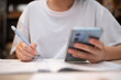 © hakase420 - スマートフォンを見ながら勉強をする中学生