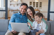 © InsideCreativeHouse - Young family looking at laptop together at home. Happy family couple and cute boy son child watching something on computer, having video call. Mother, father and kid having good time at home