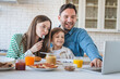 © InsideCreativeHouse - Joyful family using laptop during the breakfast in the kitchen watching cartoon have video call, everyone is happy and smiling, parents enjoy spending time with their child kid son little boy