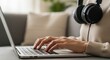 © Viktor - Female adult typing on laptop with headphones in cozy living room setting