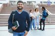 © Serhii - Smiling indian student holding books on campus