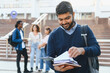 © Serhii - Indian male student holding books on campus