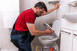 © Marko - Plumber fixing a toilet in a modern bathroom using tools and skills for repair work