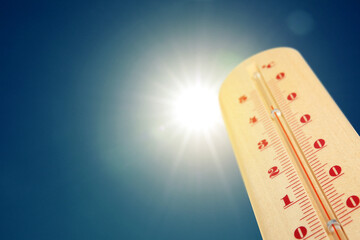 Wall Mural - thermometer showing high temperature against sky with bright sun. extremely hot weather