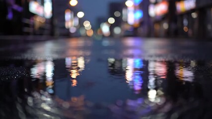 Wall Mural - A wide-angle, low-shot perspective of rain accumulating in small street puddles, reflecting blurry overhead streetlights and neon glows night, rain accumulating, background