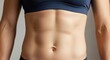 © soem - A woman's torso with a blue sports bra and black leggings, showing a toned abdominal muscle with a white background.