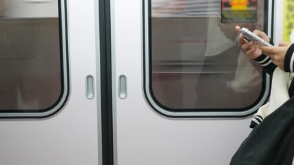 Canvas Print - view inside moving train at subway train door with passenger holding using mobile smartphone while the train is departing from the station,Tokyo railway train city life 
