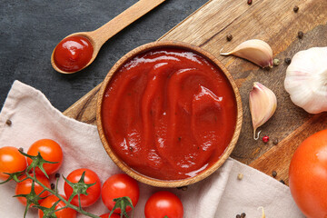 Wall Mural - Wooden tray with bowl of tasty ketchup and ingredients on blue grunge background, closeup