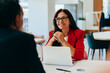 © (JLco) Julia Amaral - Woman in red jacket engaged in a professional conversation with a colleague