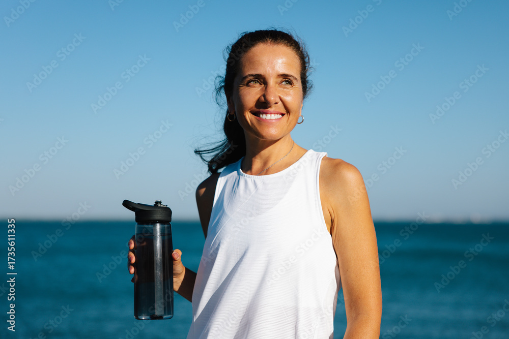 Smiling woman enjoys outdoors with a water bottle by the sea Stock ...