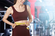 © New Africa - Athletic woman with flat belly and measuring tape in gym, closeup