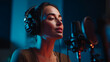 © Shahazadi - A young woman with headphones singing into a microphone in a recording studio with blue lighting
