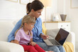 © New Africa - Telehealth. Mother and her sick daughter having online consultation with doctor via laptop on sofa at home