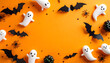 © Arif - Festive Halloween flat lay with charming bats, friendly white ghosts, and classic decorative elements arranged on a vibrant orange background, perfect for holiday celebrations