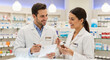 © dubogray1985 - Happy pharmacists discussing prescriptions and medications in a pharmacy.