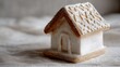 © Anastasia - Close-up of a small gingerbread house. the house is made of white sugar and has a brown roof with a lattice pattern.