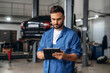 © standret - Modern digital tablet is in hands. Male mechanic is working in the car workshop
