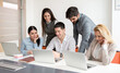 © Bojan - Group of business people gathered around young manager working on laptop developing strategy