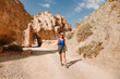 © EdNurg - Woman enjoying a hike in the stunning Charyn Canyon, Kazakhstan, surrounded by towering rock formations under a clear sky